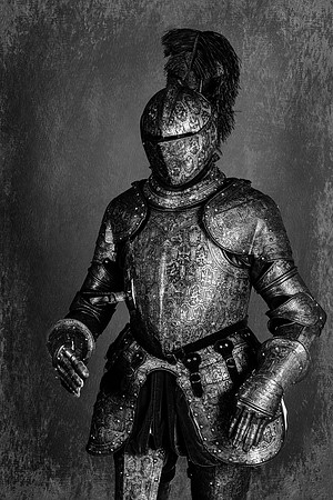 Black and white three-quarter view photograph of a Renaissance-era suit of armor standing against a dark textured background.